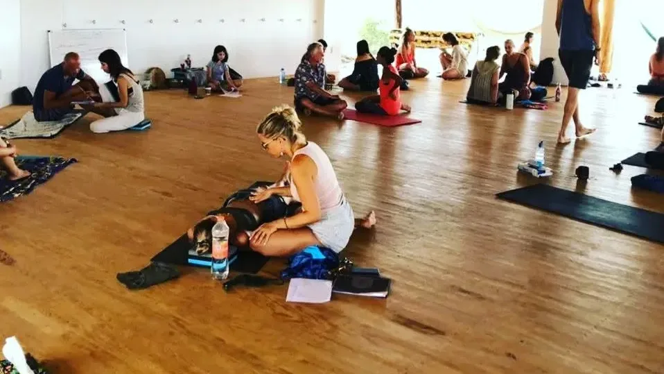 Participants practising in pairs on mats during a somatic trauma training in Mazunte, Mexico, 2022