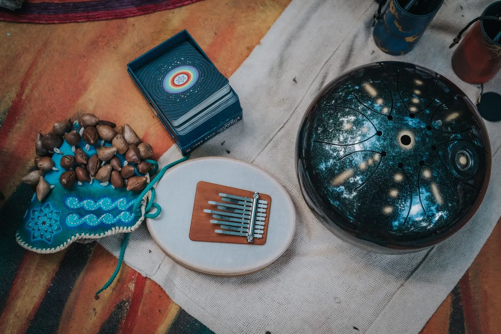 Overhead view of sound healing instruments arranged on a white cloth: a teal embroidered pouch holds, Lunita Jungle Retreat
