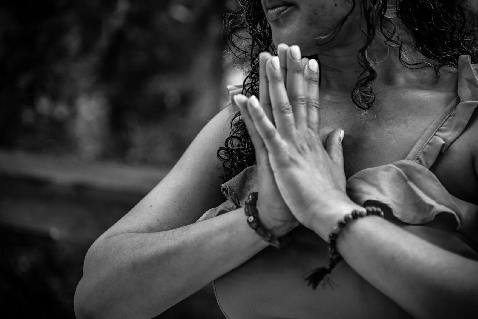 Black-and-white close-up of a woman's hands pressed to her chest in a gesture of inner focus, Lunita Jungle Retreat