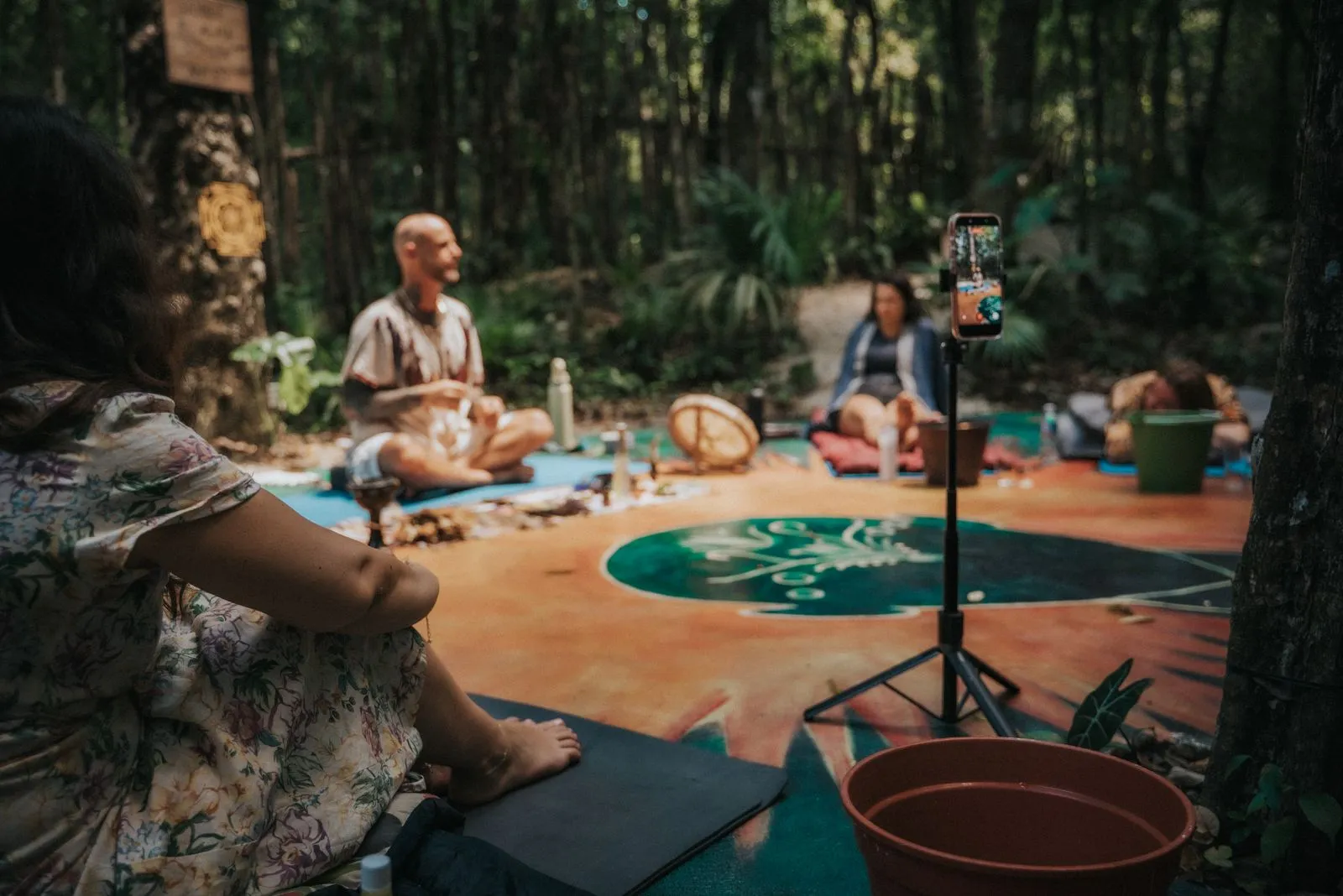 A group seated on woven mats in a jungle clearing, dappled light filtering through dense canopy onto, Lunita Jungle Retreat