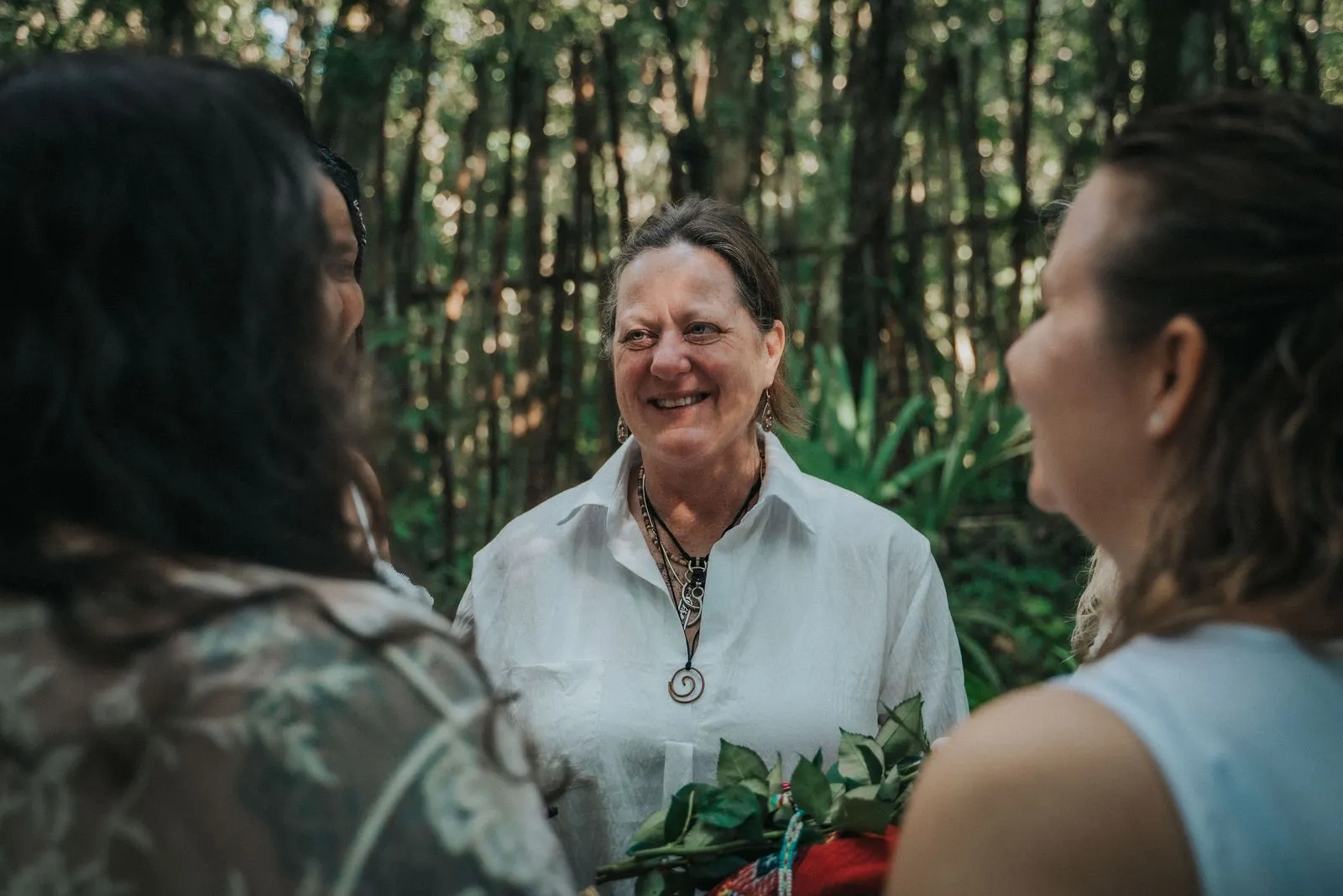 Three women stand in a circle among tall bamboo stalks, dappled morning light filtering, Lunita Jungle Retreat