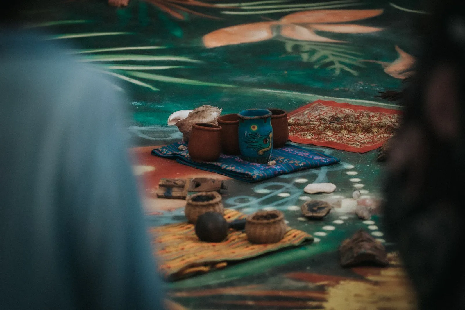Clay cacao vessels and woven textiles arranged on a green floor, Lunita Jungle Retreat