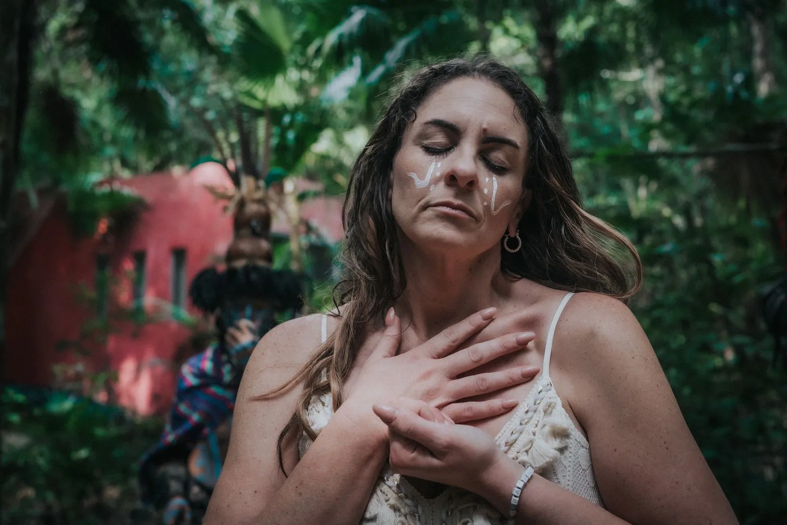 Two people lie on dark ground in close contact, one wearing a burgundy wrap, Lunita Jungle Retreat