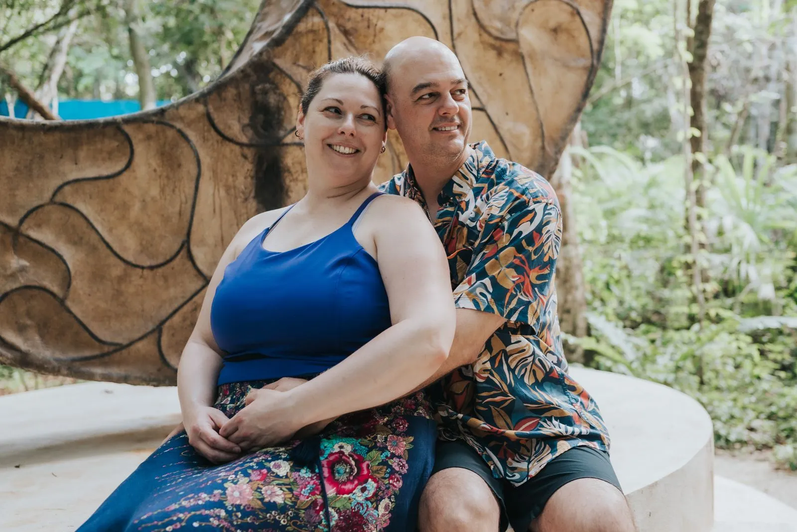 A man and woman sit close together on a curved concrete bench in the jungle, Lunita Jungle Retreat