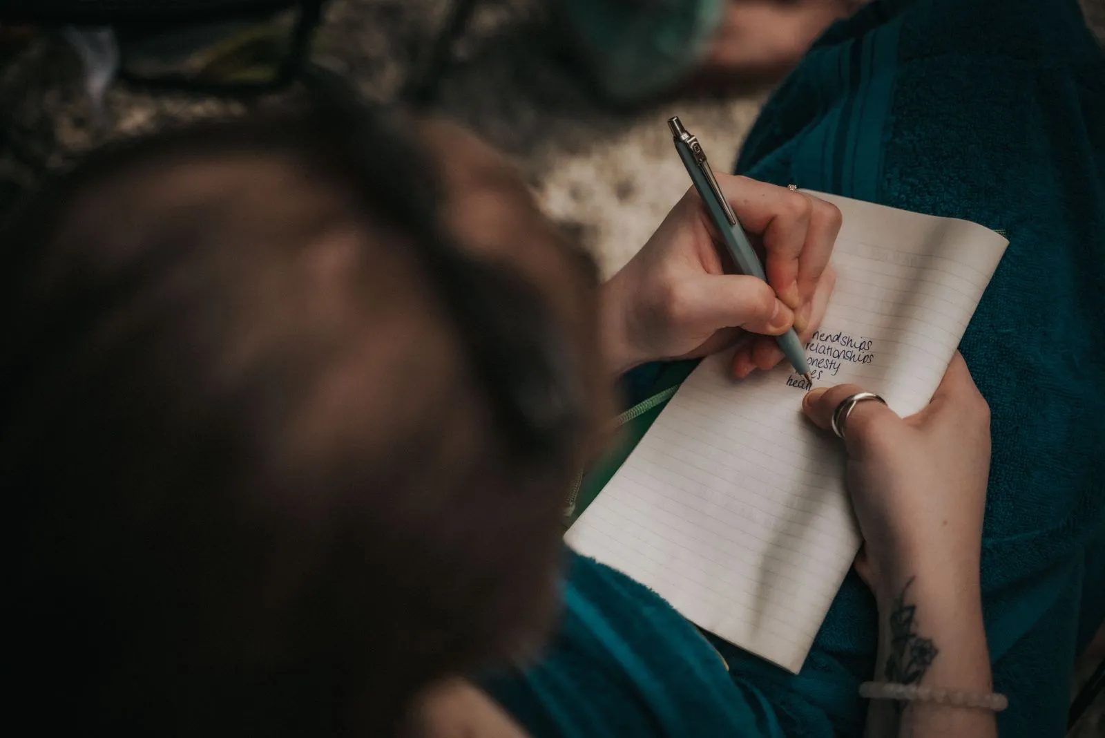 A person in a teal shirt writes in a lined notebook with a pen, Lunita Jungle Retreat