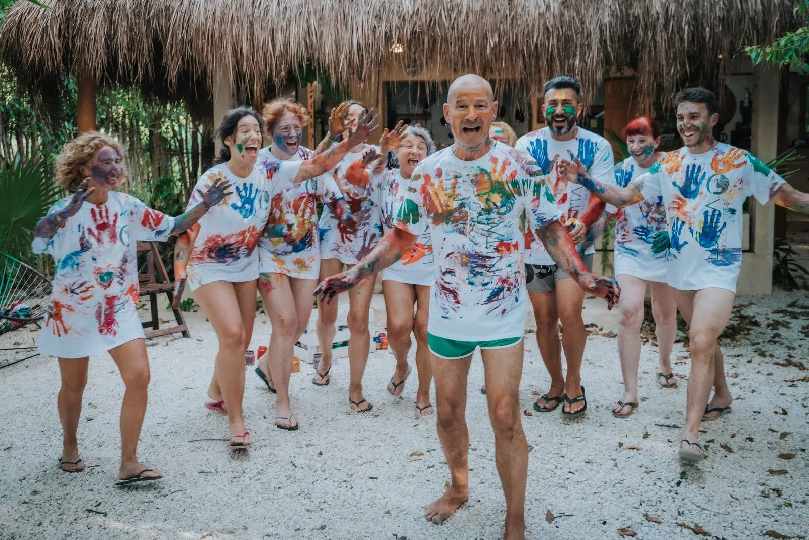 Nine people in white t-shirts covered with handprints in red, blue, orange, Lunita Jungle Retreat