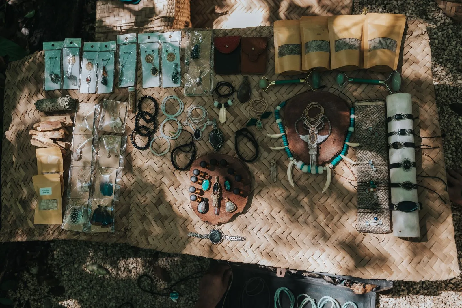 Overhead view of a woven palm mat displaying an organized arrangement of handmade jewelry, Lunita Jungle Retreat