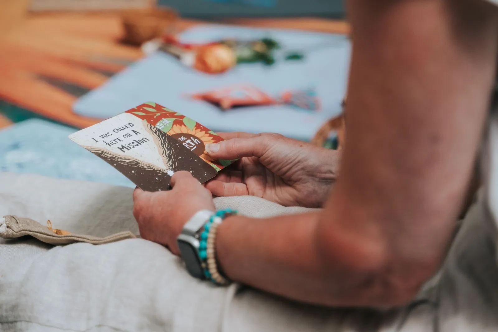 Hands hold an oracle or tarot card with an image of a figure and gold text during what appears to be, Lunita Jungle Retreat