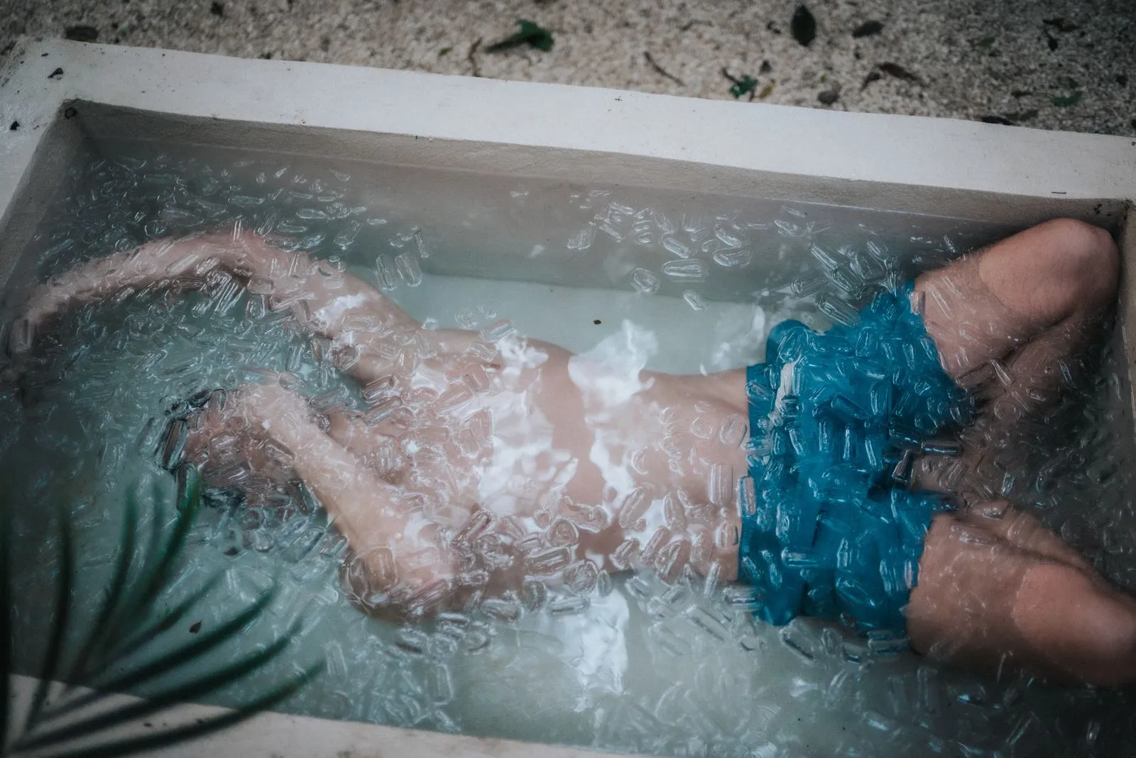 Two hands submerged in ice water inside a white tub, fingers splayed, Lunita Jungle Retreat