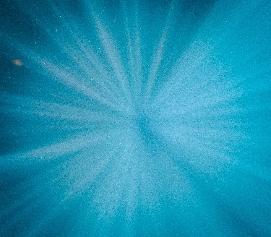 Underwater view looking upward through turquoise water toward sunlight, Lunita Jungle Retreat